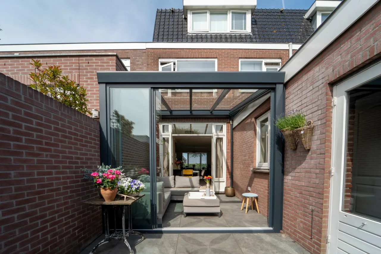 Aluxe Trendline overkapping met glazen dak boven een terras met loungeset