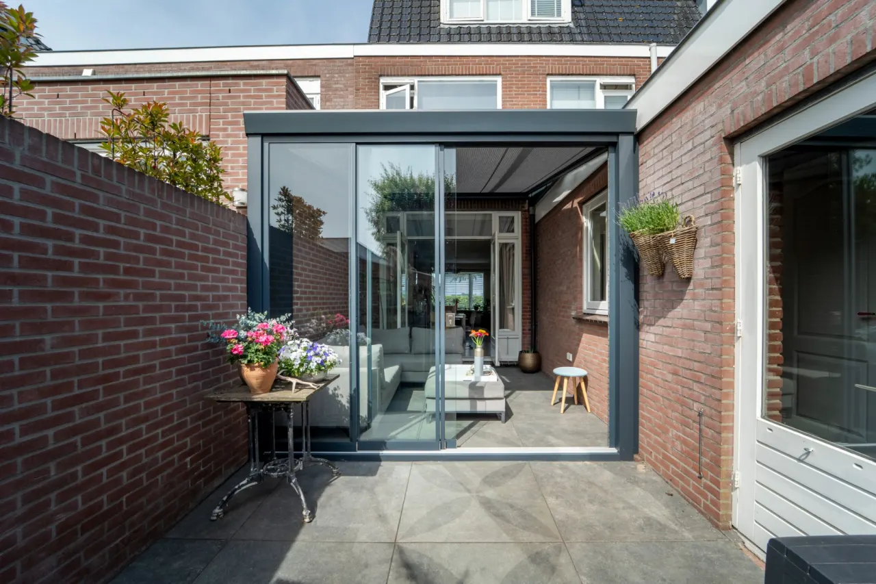 Aluxe Trendline overkapping met glazen schuifwanden en zithoek op het terras